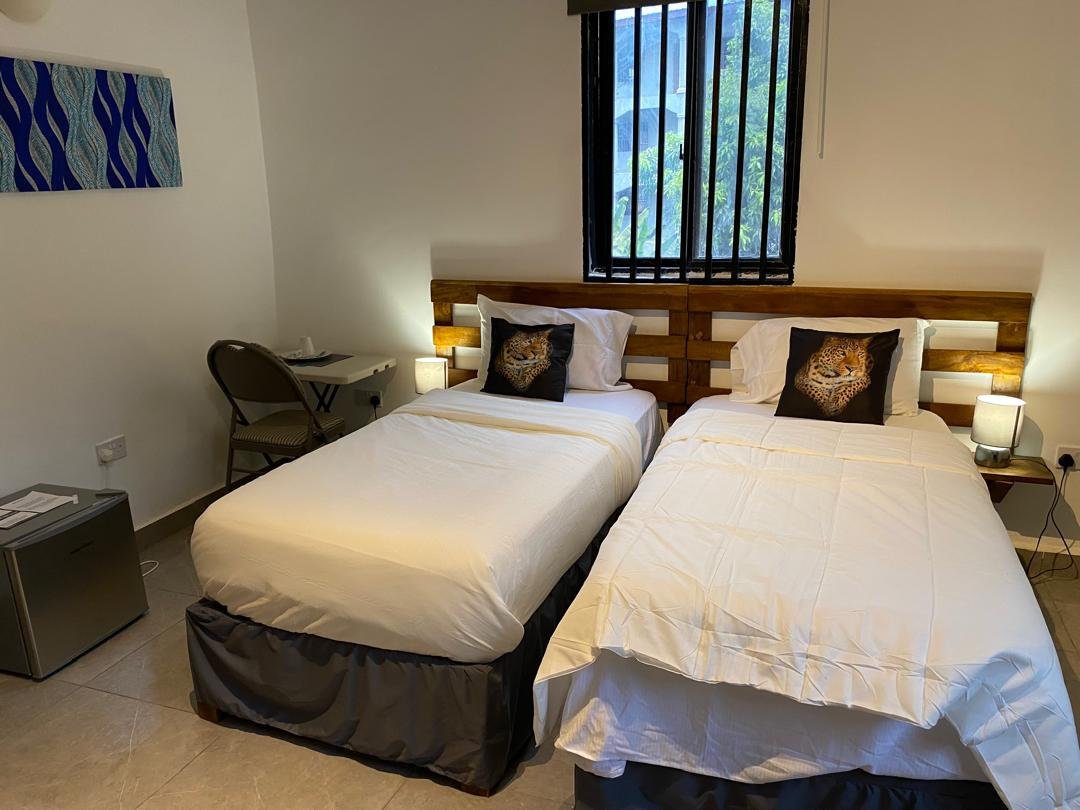 Twin beds with blue artwork and mini fridge