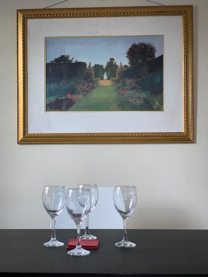Dining table laid with glassware beneath framed art
